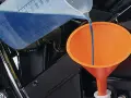Versando liquido refrigerante blu in un imbuto arancione per diluirlo.