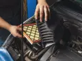 Mani che sostituiscono un filtro aria sporco nel vano motore di un'auto.