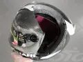 Casco da moto con calotta in fibra di carbonio e abs o policarbonato, visiera trasparente e interni rossi. La calotta presenta una crepa.