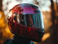Casco da moto rosso lucido, riflessi di alberi e cielo. Non è un luogo dove si buttano i caschi da moto, ma un simbolo di avventura.