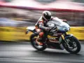 Un pilota in tuta da corsa arancione e nera sfreccia su una moto da competizione. Potrebbe essere la tuta più costosa al mondo, ma la velocità è impagabile.