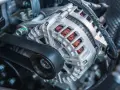 Il componente metallico argentato con fili di rame visibili è un alternatore, essenziale per generare elettricità nel motore.