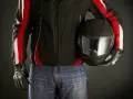 Motociclista con giacca nera e strisce rosse, jeans e casco nero. Le giacche ad uso motociclistico sono pronte per la strada.