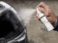 Mano spruzza spray idrorepellente sul casco Shoei. Il casco non deve essere pulito con benzina, ma con prodotti specifici per la visiera.