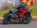 Un motociclista sfreccia su una moto sportiva rossa, tra le migliori moto sportive, con un casco moderno e jeans.