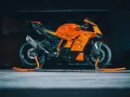 La KTM 890 Duke GP, arancione e nera, pronta per la pista, con scarico Akrapovič e cavalletti arancioni.