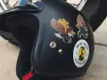 Casco nero con adesivi: un'aquila, un personaggio a strisce e un serpente in un barattolo. Si possono attaccare adesivi sul casco per personalizzarlo.