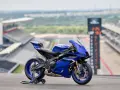 Yamaha R9, blu, su un cavalletto, con sfondo di un circuito. Dettagli tecnici da scoprire.