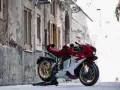 MV Agusta rossa e bianca, la più costosa, su un cavalletto in un vicolo storico.