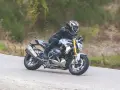 Motociclista in sella a una BMW R 1250 R, affronta una curva. Nessun difetto visibile in questa immagine.