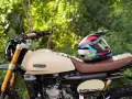 Casco colorato appoggiato su una moto Caballero Rally color crema. Perfetta per avventure, queste moto facili da guidare ti portano ovunque.