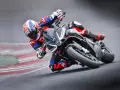 Un pilota in piega su una Aprilia Tuono 660 Factory, con tuta rossa e blu, affronta una curva su pista.