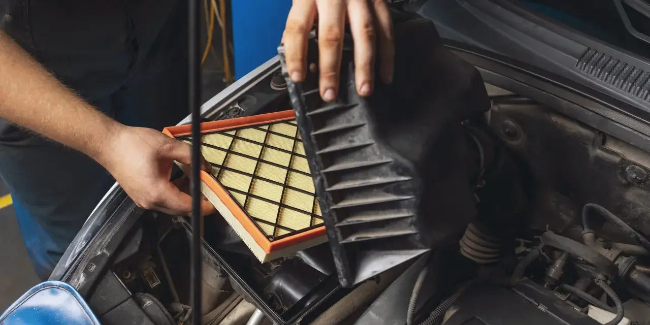 Mani che sostituiscono un filtro aria sporco nel vano motore di un'auto.