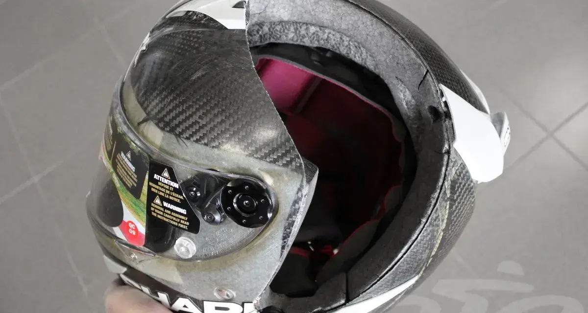 Casco da moto con calotta in fibra di carbonio e abs o policarbonato, visiera trasparente e interni rossi. La calotta presenta una crepa.