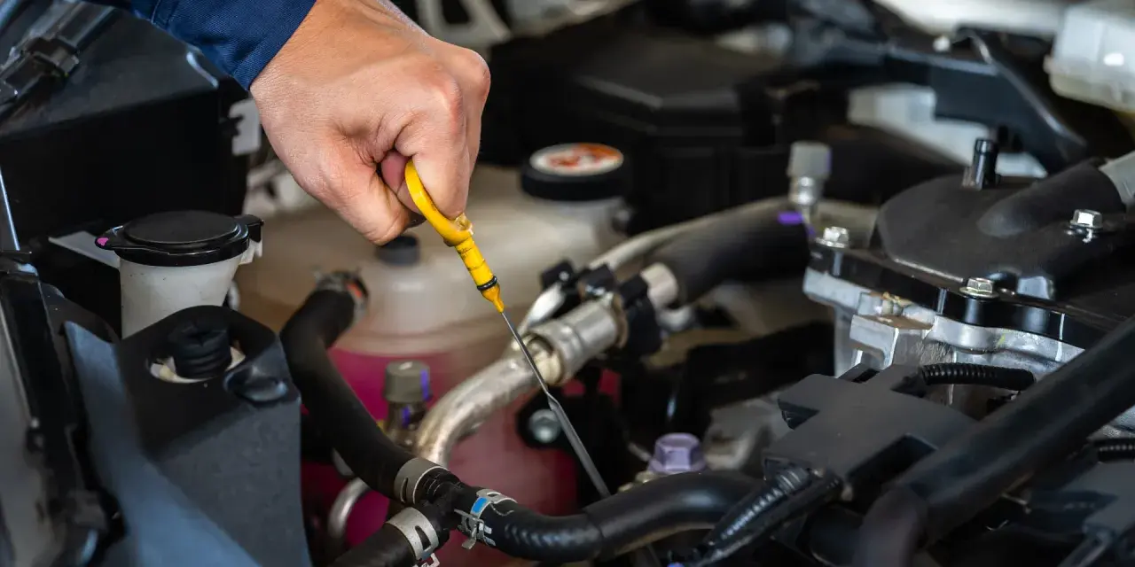 Controllo dei liquidi motore: una mano estrae l'astina per verificare il livello dell'olio.