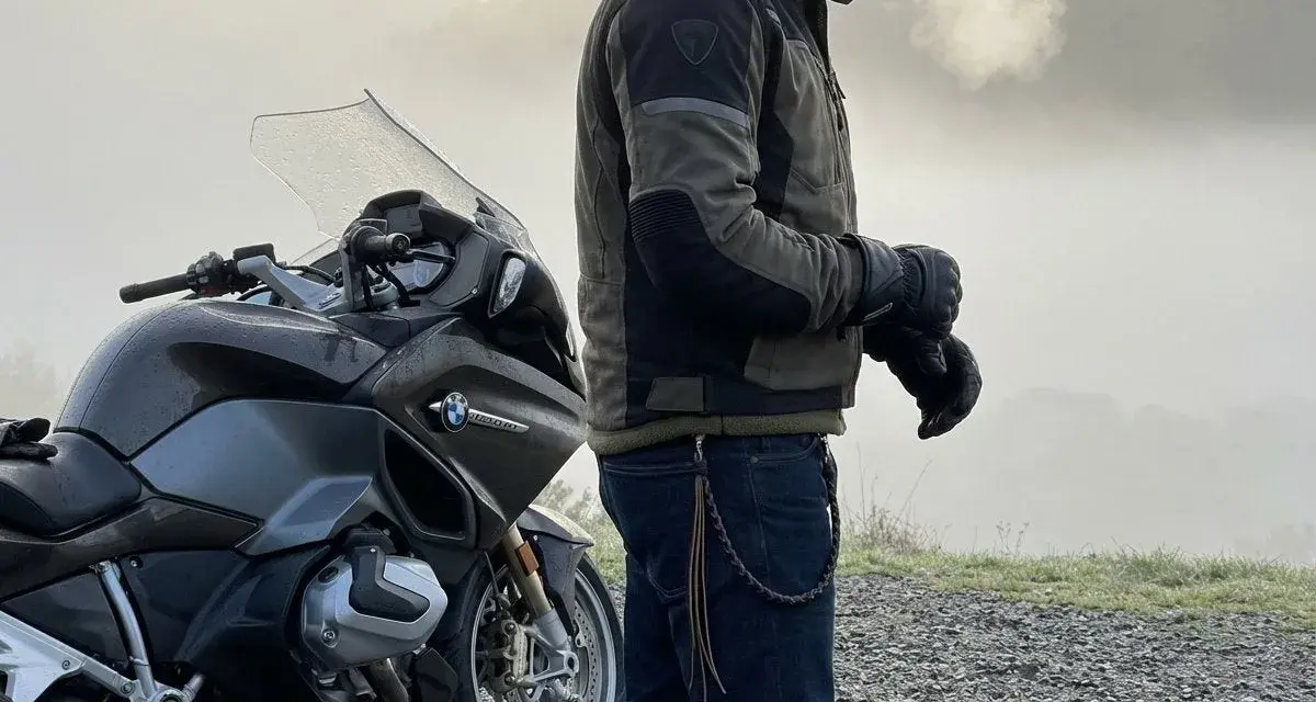 Motociclista con giacca tecnica e jeans, pronto per un'avventura. Ecco come vestirsi per andare in moto in ogni condizione.