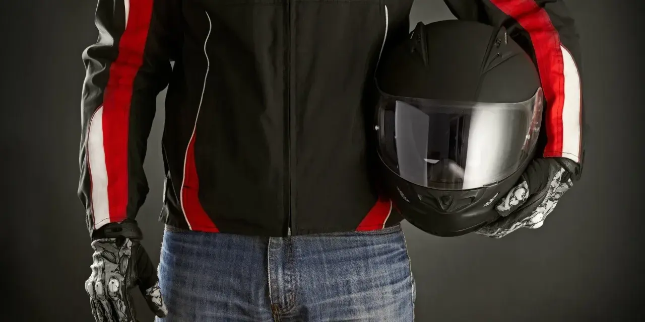 Motociclista con giacca nera e strisce rosse, jeans e casco nero. Le giacche ad uso motociclistico sono pronte per la strada.