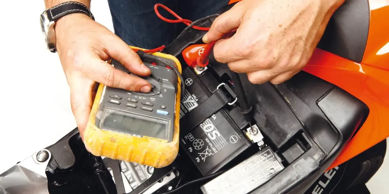 Si accende il quadro ma la moto non parte. Un tecnico controlla la batteria con un multimetro, sperando di risolvere il problema.