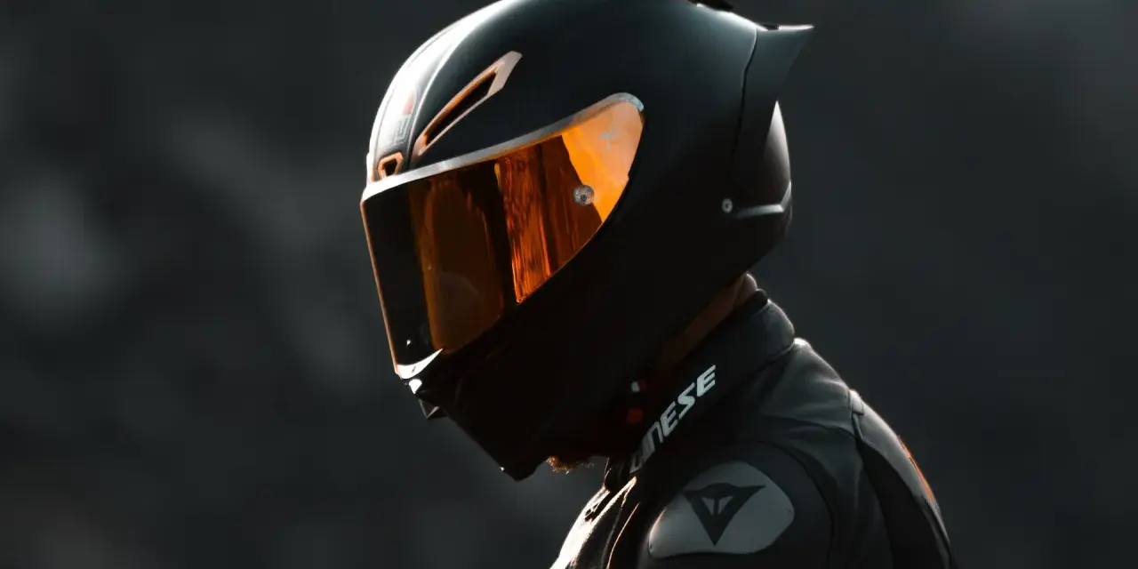 Casco da moto integrale nero con visiera arancione riflettente, pronto per la pista.