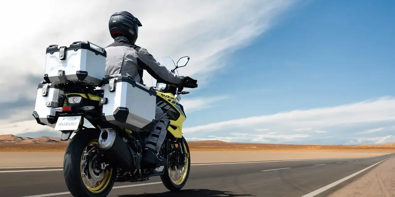 Motociclista con abbigliamento tecnico, ideale per capire come vestirsi in moto d'estate, viaggia su una Suzuki con borse laterali e posteriori.
