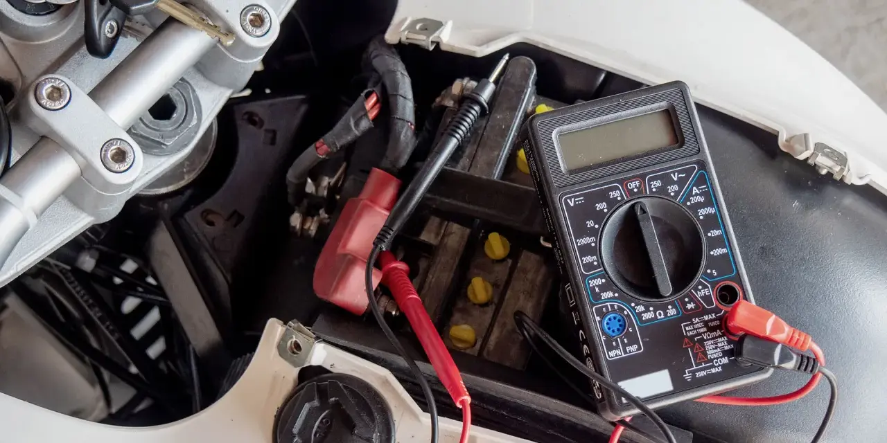 Multimetro collegato alla batteria di uno scooter per verificarne lo stato, un passo fondamentale per capire come caricare batteria scooter.