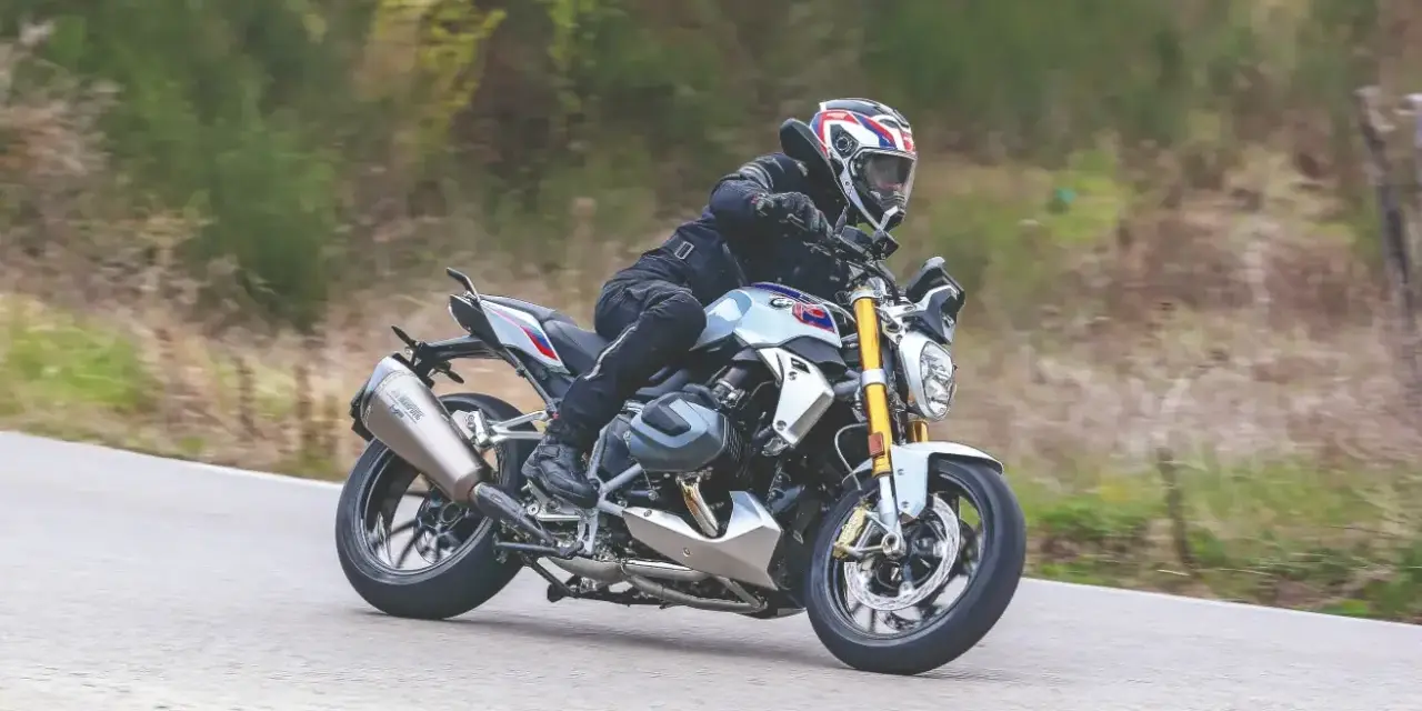 Motociclista in sella a una BMW R 1250 R, affronta una curva. Nessun difetto visibile in questa immagine.
