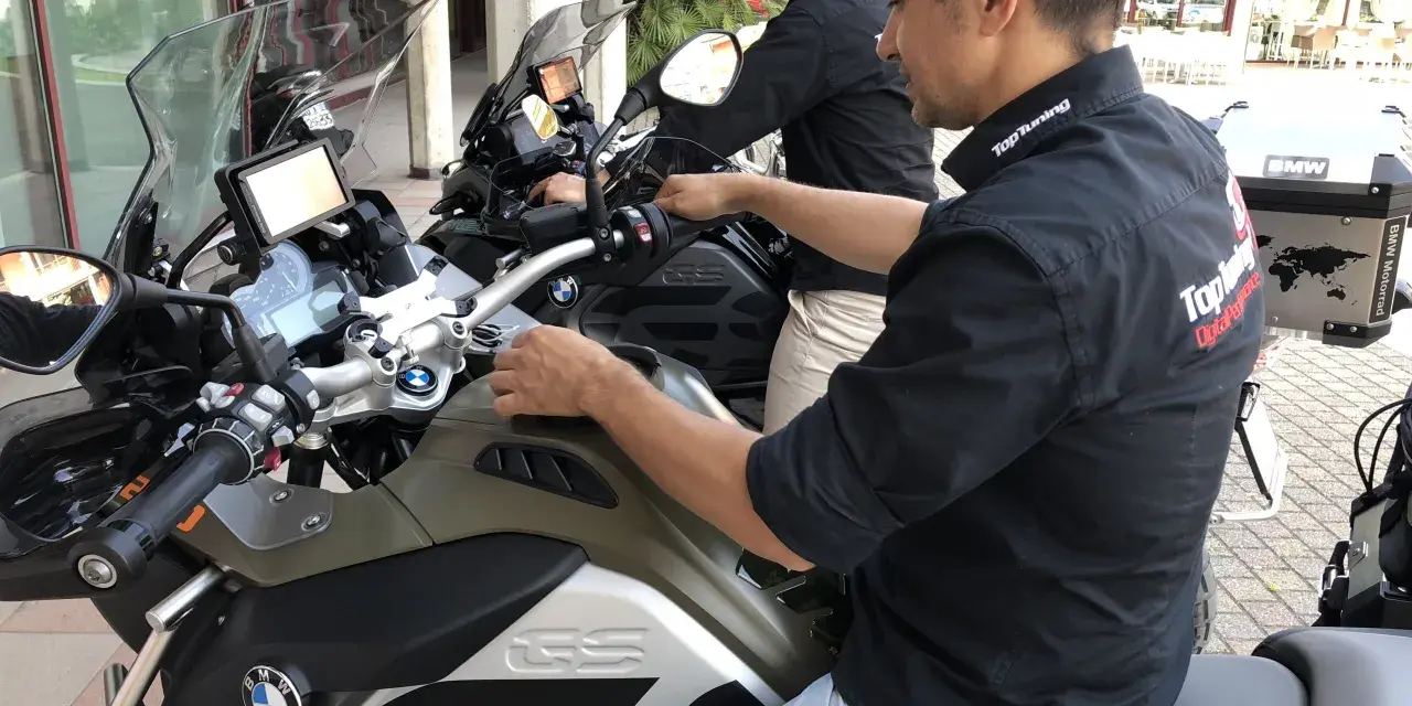 Due uomini in moto BMW, forse in fase di rodaggio, con abbigliamento tecnico. Il significato del rodaggio è fondamentale per la longevità del mezzo.