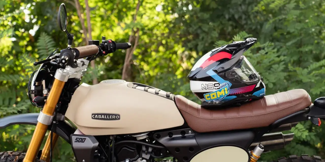 Casco colorato appoggiato su una moto Caballero Rally color crema. Perfetta per avventure, queste moto facili da guidare ti portano ovunque.