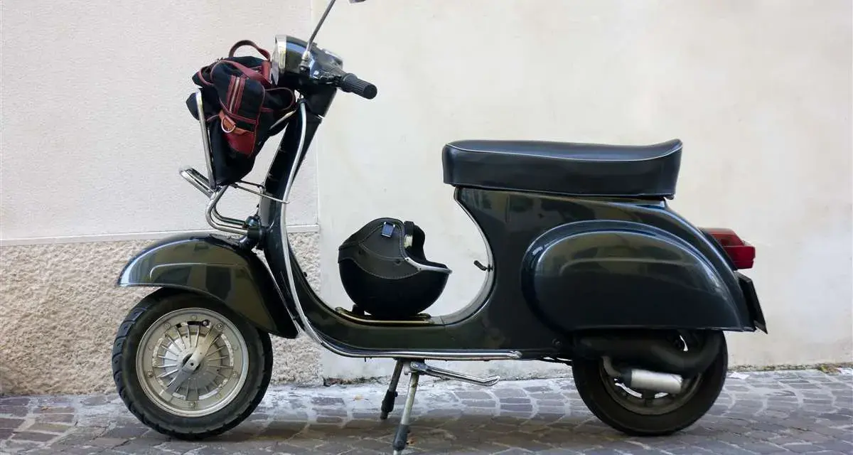 Moto d'epoca, un classico intramontabile. Dopo quanti anni mantiene ancora il suo fascino? Un casco e una borsa completano il look.
