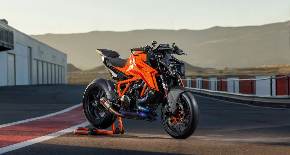 KTM 1290 Duke arancione su un cavalletto, pronta per sfrecciare su un circuito al tramonto.