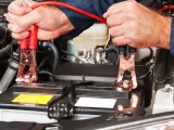 Mani che collegano i cavi per avviare moto con batteria auto.