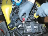 Mani guantate collegano un mantenitore di carica moto sempre collegato alla batteria.