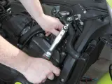 Mani che usano una chiave dinamometrica per il cambio candele di una moto.