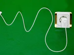 Cavo bianco collegato a una presa elettrica dorata. Si può lasciare il caricabatterie attaccato per avere sempre energia.