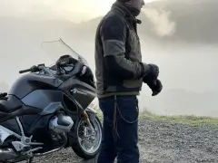 Motociclista con giacca tecnica e jeans, pronto per un'avventura. Ecco come vestirsi per andare in moto in ogni condizione.