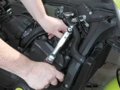 Mani che usano una chiave dinamometrica per il cambio candele di una moto.
