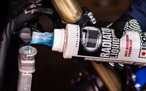 Versando liquido radiatore moto, uguale a quello per auto, nel serbatoio di raffreddamento.