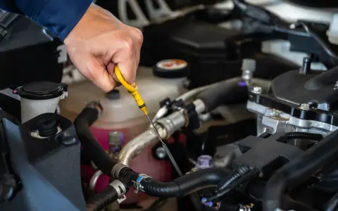 Controllo dei liquidi motore: una mano estrae l'astina per verificare il livello dell'olio.