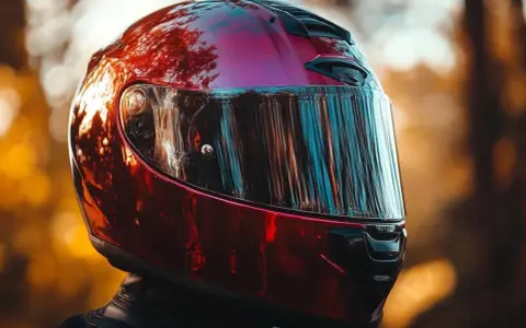 Casco da moto rosso lucido, riflessi di alberi e cielo. Non è un luogo dove si buttano i caschi da moto, ma un simbolo di avventura.