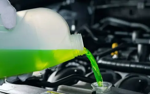 Versamento di liquido refrigerante verde in un radiatore. Le cause di un radiatore senza acqua possono essere perdite o evaporazione.