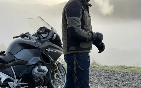Motociclista con giacca tecnica e jeans, pronto per un'avventura. Ecco come vestirsi per andare in moto in ogni condizione.