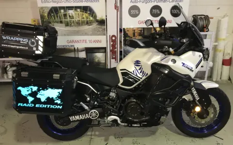 Moto Yamaha Super Ténéré con valigie personalizzate, una con mappa del mondo luminosa e scritta "Raid Edition". Il wrapping con acqua è un'idea per proteggere la moto.