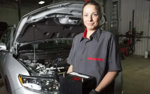 Meccanica sorridente con una nuova batteria, pronta per mostrare come montare una batteria auto.