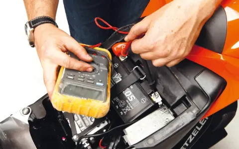 Si accende il quadro ma la moto non parte. Un tecnico controlla la batteria con un multimetro, sperando di risolvere il problema.