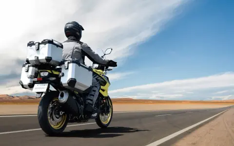 Motociclista con abbigliamento tecnico, ideale per capire come vestirsi in moto d'estate, viaggia su una Suzuki con borse laterali e posteriori.