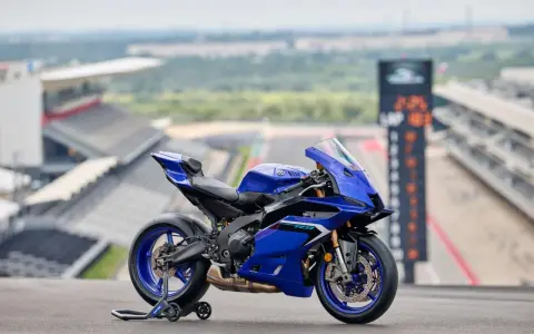 Yamaha R9, blu, su un cavalletto, con sfondo di un circuito. Dettagli tecnici da scoprire.