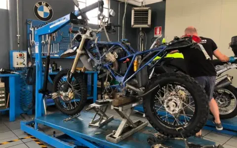 Officina BMW: moto smontata su sollevatore, in attesa del raffreddamento motore. Attrezzi e meccanico al lavoro.