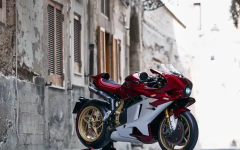 MV Agusta rossa e bianca, la più costosa, su un cavalletto in un vicolo storico.
