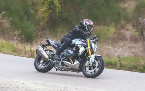 Motociclista in sella a una BMW R 1250 R, affronta una curva. Nessun difetto visibile in questa immagine.