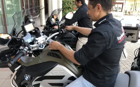 Due uomini in moto BMW, forse in fase di rodaggio, con abbigliamento tecnico. Il significato del rodaggio è fondamentale per la longevità del mezzo.